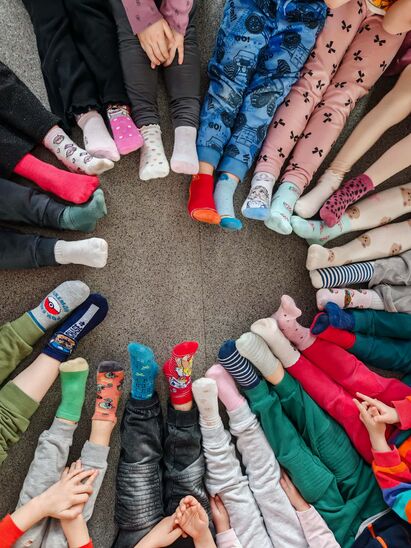 dzieci siedzące na podłodze w kole, na stopach kolorowe skarpetki nie do pary