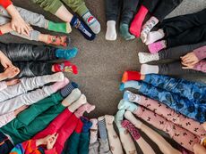 dzieci siedzące na podłodze w kole, na stopach kolorowe skarpetki nie do pary