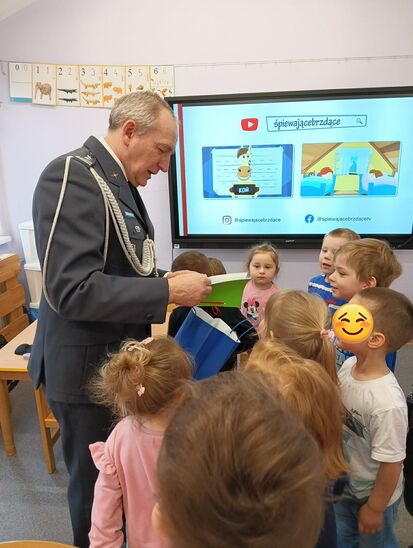 grupa dzieci w towarzystwie starszego mężczyzny ubranego w mundur wojskowy