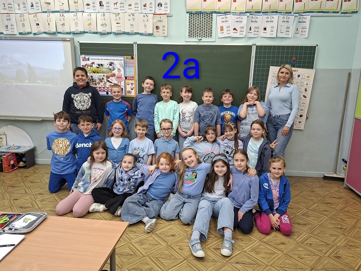Na zdjęciu widoczna jest klasa 2a wraz z wychowawczynią. Uczniowie ubrani są na niebiesko, solidaryzując się z osobami w spektrum autyzmu. Wszyscy pozują w sali lekcyjnej, tworząc radosną i zgraną grupę