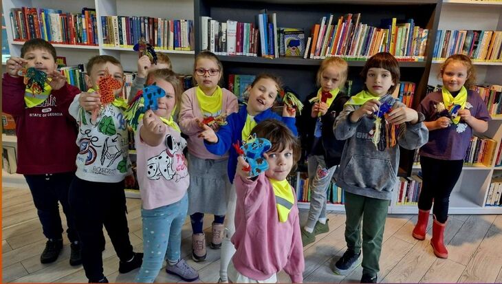 grupa dzieci w bibliotece, w dłoniach trzymają własnego jednorożca