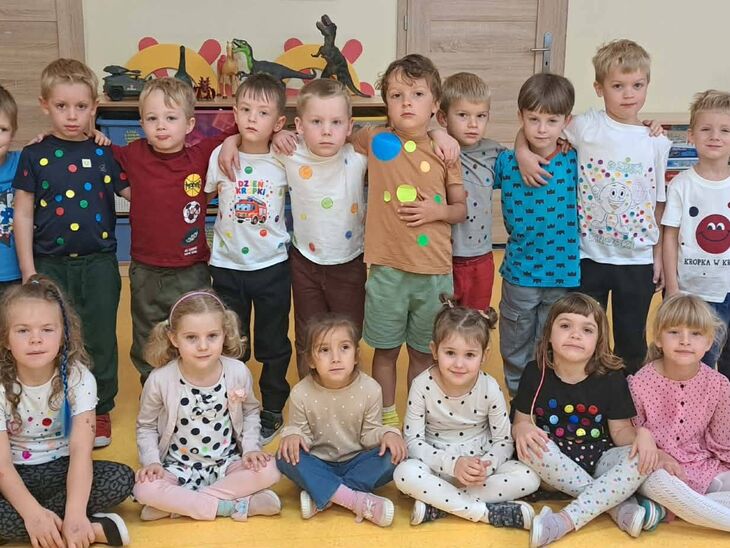 dzieci stojące w szeregu, w kolorowych koszulkach z motywami kropek