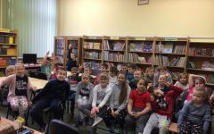 Czytanie bajek w bibliotece. Dzieci siedzą na krzesłach i słuchają